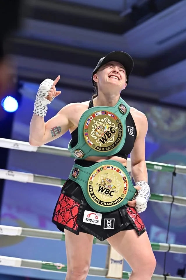 Ellie Bouttell celebrating with two championship belts