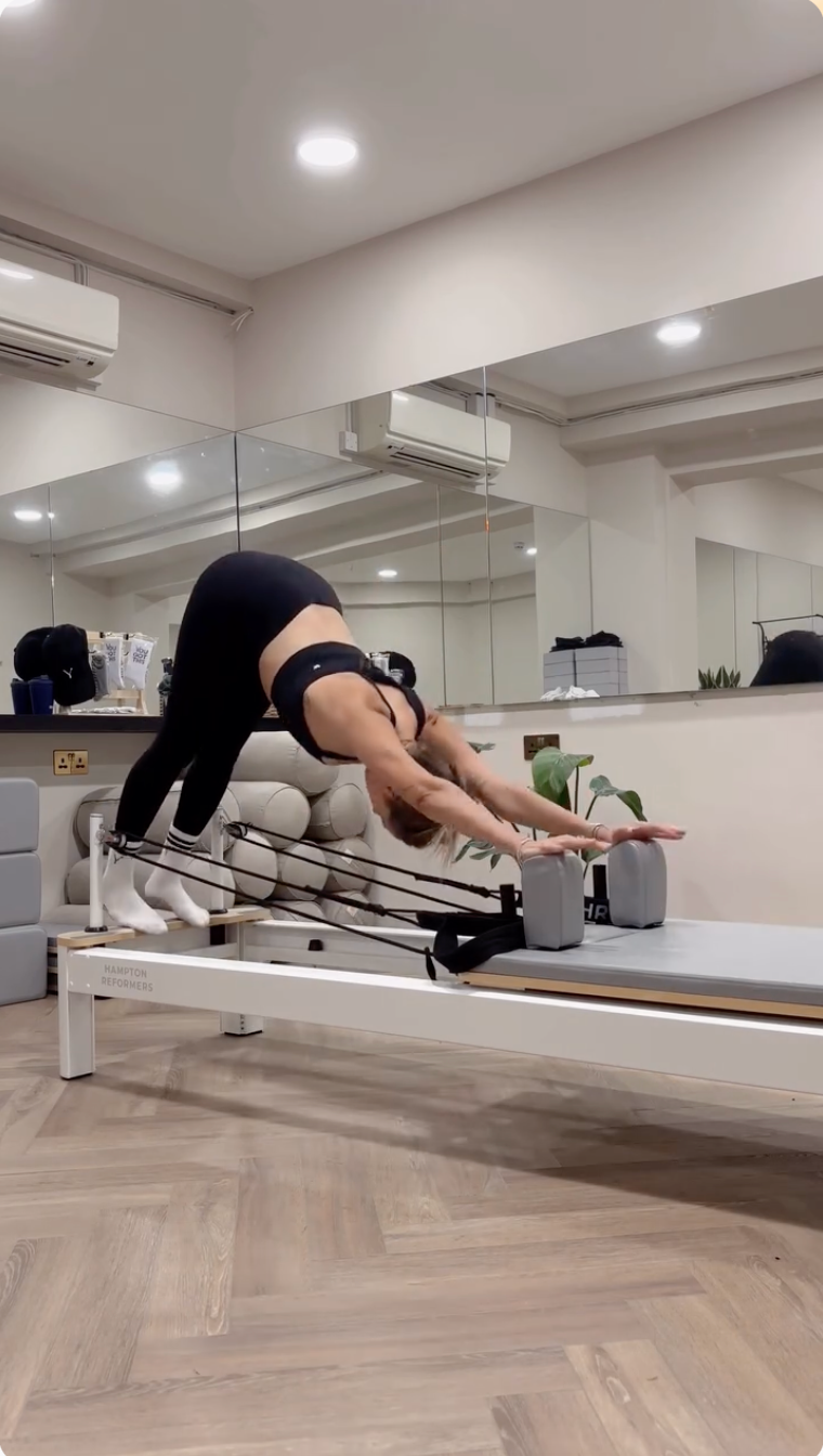 Person practising a controlled Pilates movement in a black set