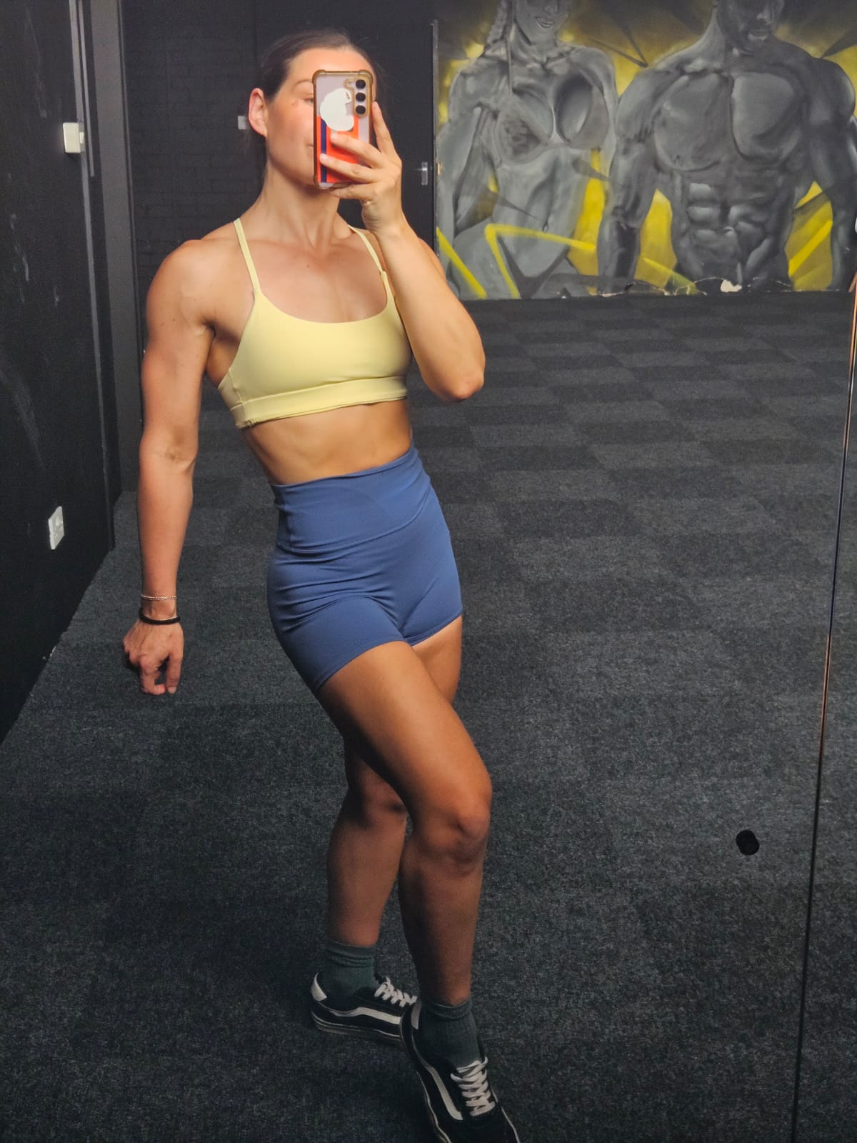 Athlete wearing a Butter Cream bra and Coastal Blue shorts in a gym mirror