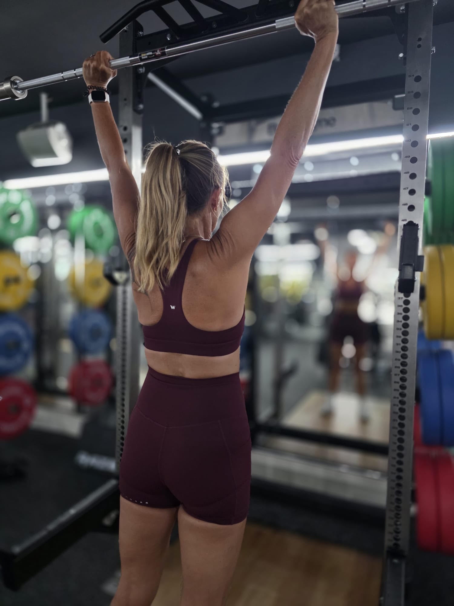 Athlete hanging from a gym bar in a Burgundy training set