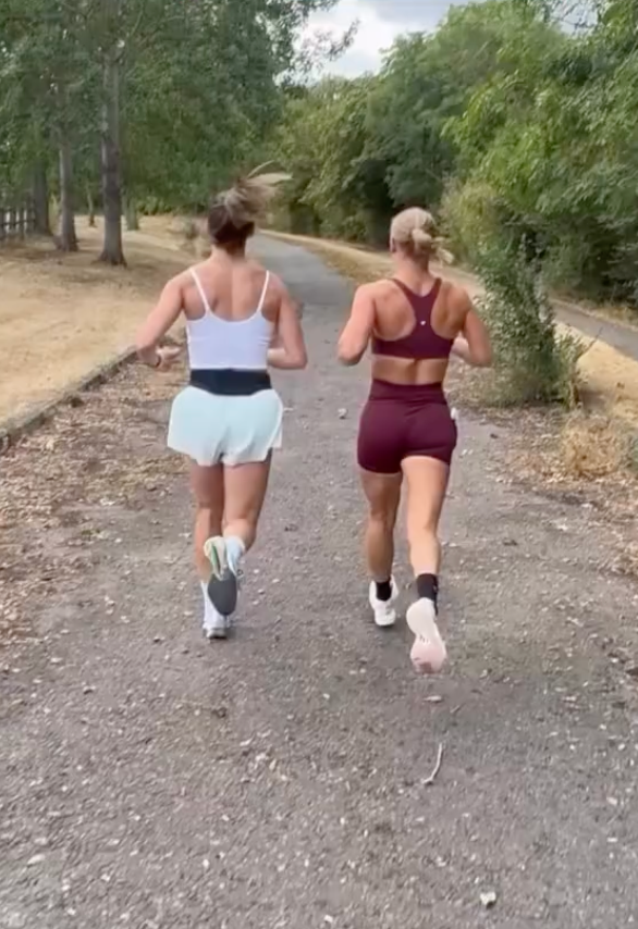 Two runners moving along an outdoor trail with one wearing a Burgundy set